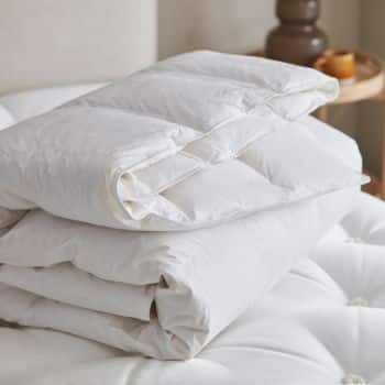a stack of white duvets on a bed