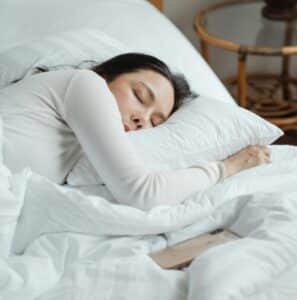 Woman in White Long Sleeved Shirt Lying on Bed
